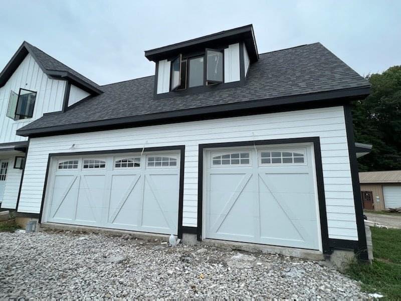 White carriage-style garage doors freshly installed on a three-car garage